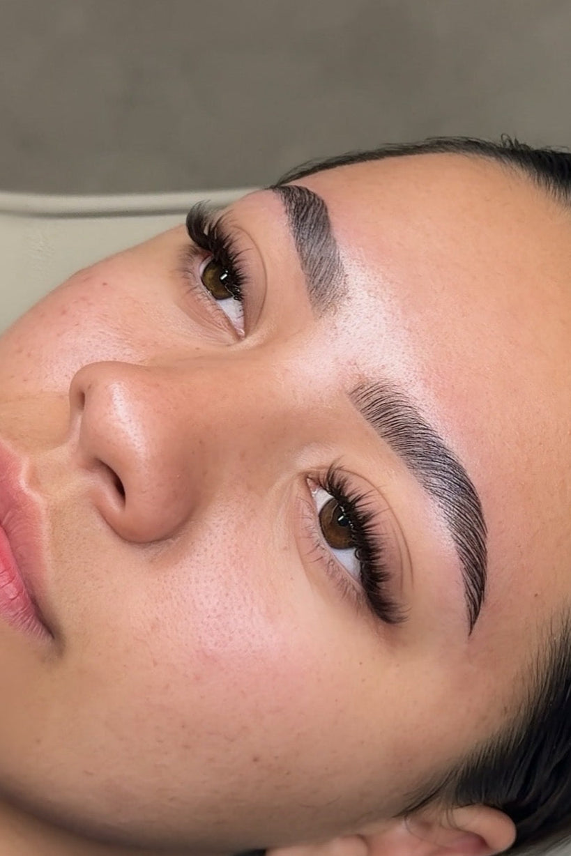 Close-up of a person with well-groomed eyebrows and pink lipstick.